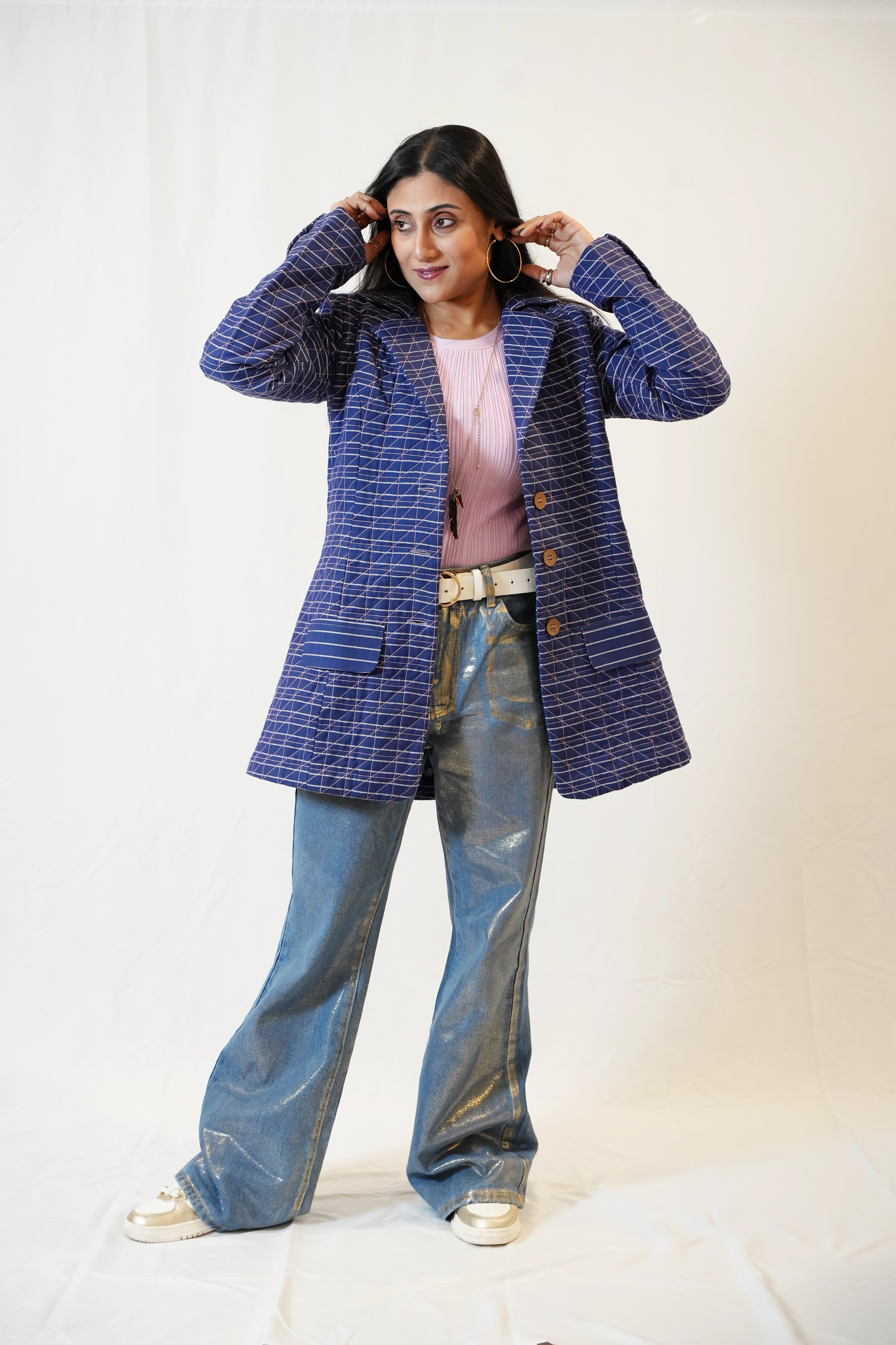 Person wearing a blue quilted blazer, pink top against a white background